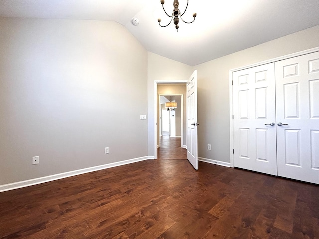 unfurnished bedroom featuring a closet, an inviting chandelier, baseboards, vaulted ceiling, and dark wood-type flooring