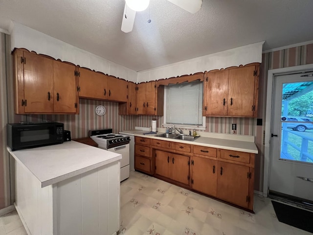 kitchen with brown cabinetry, light countertops, white range with electric stovetop, a sink, and black microwave