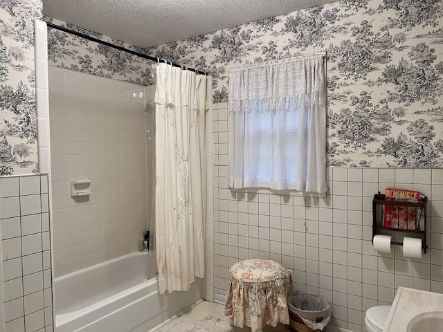 bathroom featuring shower / bathtub combination with curtain, tile patterned floors, toilet, a textured ceiling, and wallpapered walls