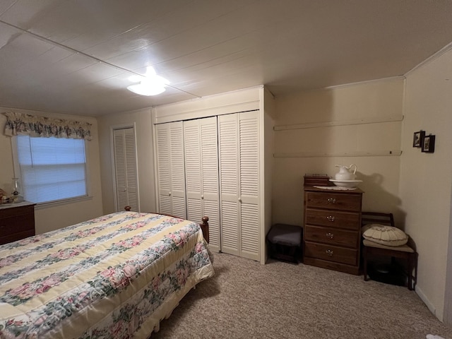 bedroom with multiple closets and carpet flooring