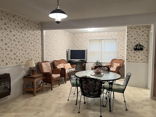 dining area with wallpapered walls, heating unit, wainscoting, and light floors
