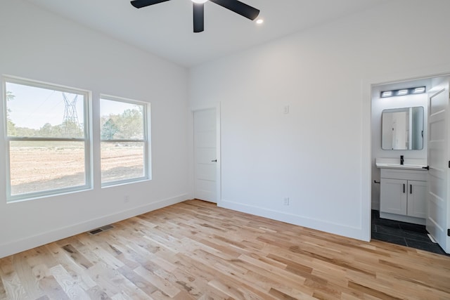 unfurnished bedroom with a sink, light wood-style floors, ensuite bathroom, visible vents, and baseboards