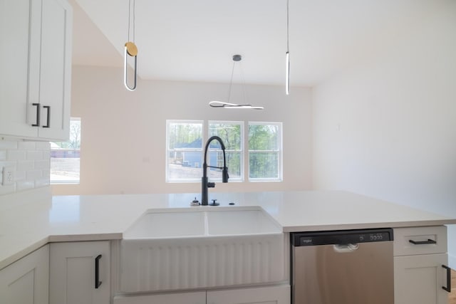 kitchen featuring tasteful backsplash, light countertops, white cabinets, dishwasher, and a sink