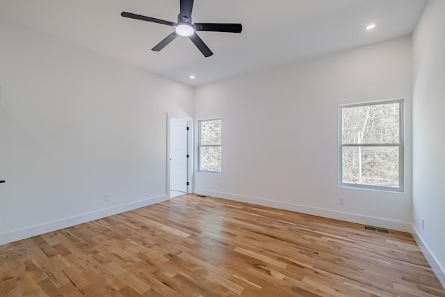 spare room featuring light wood finished floors, a ceiling fan, visible vents, and baseboards