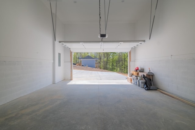 garage with a garage door opener, concrete block wall, and electric panel