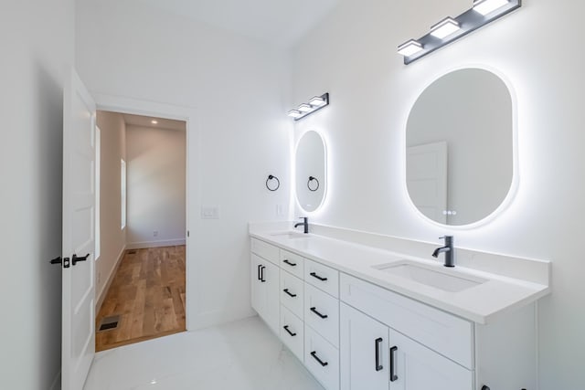 full bathroom featuring double vanity, visible vents, baseboards, and a sink