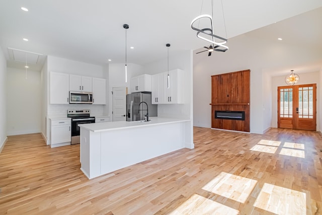 kitchen with appliances with stainless steel finishes, tasteful backsplash, light countertops, and white cabinets