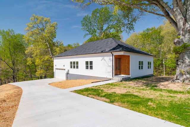 view of front of home featuring a garage, driveway, and roof with shingles
