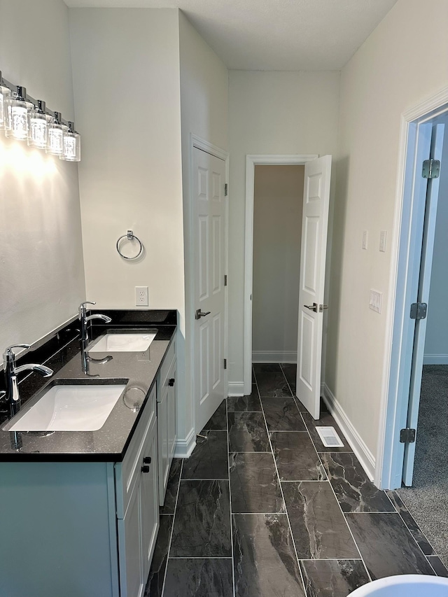 bathroom featuring a sink, baseboards, and marble finish floor