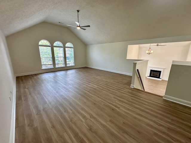 unfurnished living room featuring baseboards, ceiling fan with notable chandelier, a textured ceiling, and wood finished floors