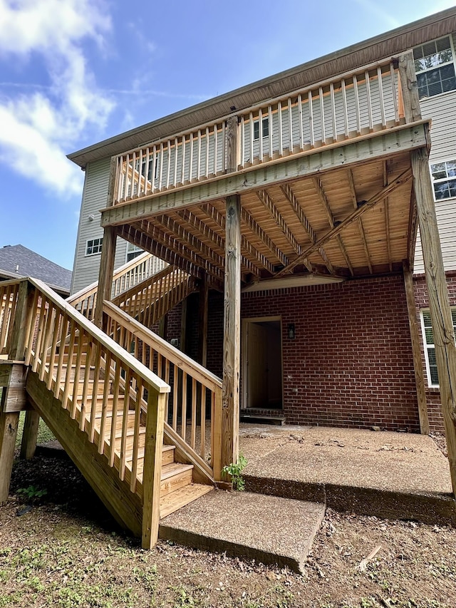 rear view of property with stairs, brick siding, and a deck