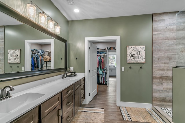 full bath with double vanity, wood finished floors, walk in shower, and a sink