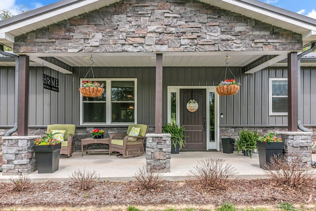 doorway to property featuring a porch, board and batten siding, and stone siding