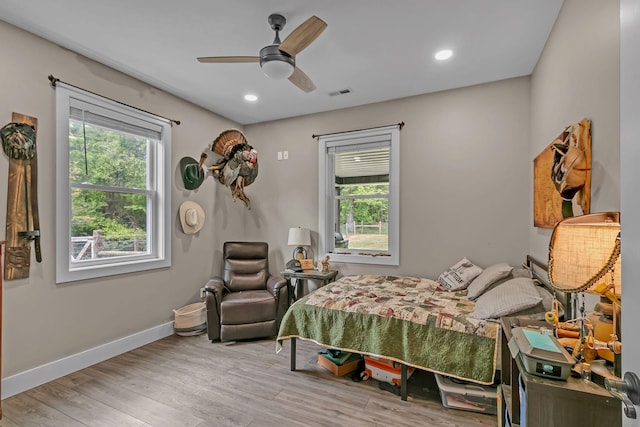 bedroom with visible vents, wood finished floors, multiple windows, and baseboards