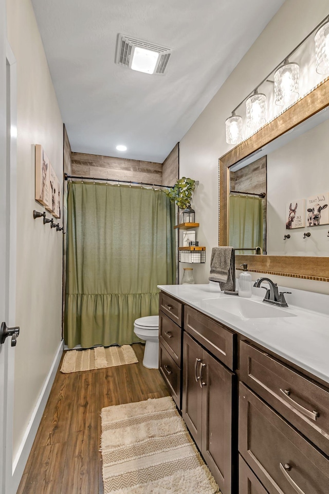 full bathroom featuring visible vents, baseboards, toilet, wood finished floors, and vanity
