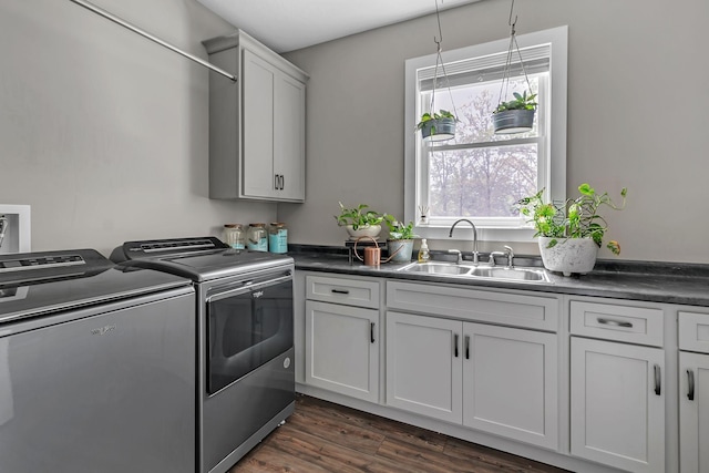 washroom featuring separate washer and dryer, a sink, cabinet space, and dark wood finished floors