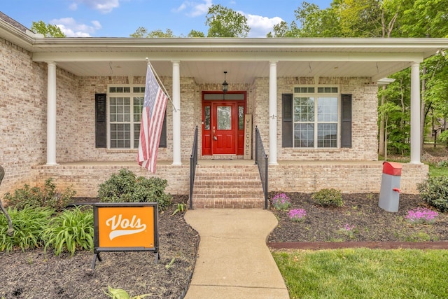 property entrance with covered porch and brick siding