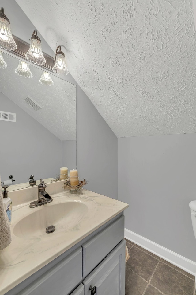 bathroom with tile patterned floors, a textured ceiling, visible vents, and vanity
