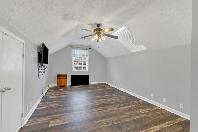 additional living space featuring baseboards, wood finished floors, ceiling fan, and a textured ceiling