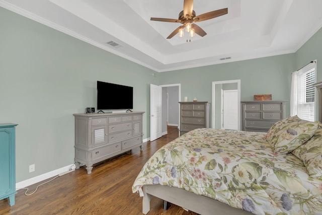 bedroom featuring visible vents, a tray ceiling, and dark wood-style floors