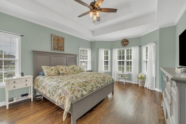 bedroom featuring dark wood-type flooring, a raised ceiling, crown molding, and baseboards