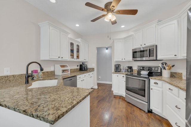 kitchen with stainless steel appliances, white cabinets, ceiling fan, a sink, and a peninsula