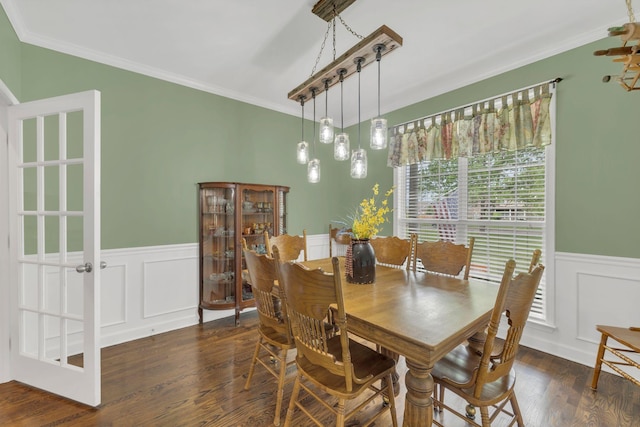 dining area featuring wainscoting, ornamental molding, wood finished floors, and a decorative wall