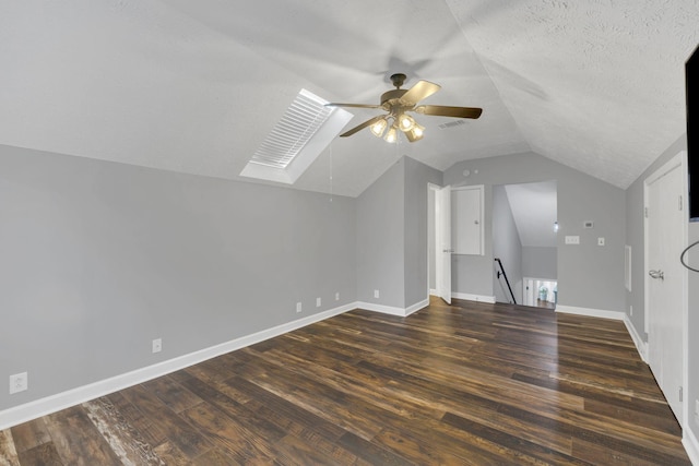 additional living space featuring vaulted ceiling with skylight, ceiling fan, visible vents, dark wood-style floors, and baseboards