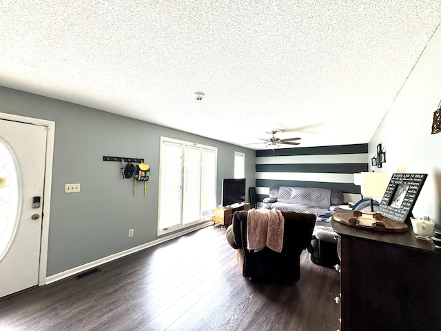 living room with a textured ceiling, visible vents, ceiling fan, baseboards, and dark wood-type flooring