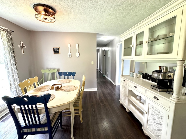 dining room featuring dark wood-style floors, a textured ceiling, and baseboards