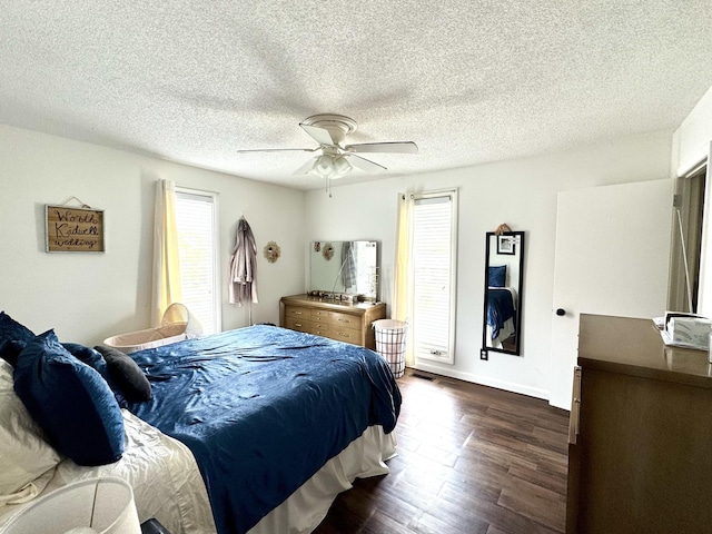bedroom featuring dark wood-style flooring, a ceiling fan, baseboards, and a textured ceiling