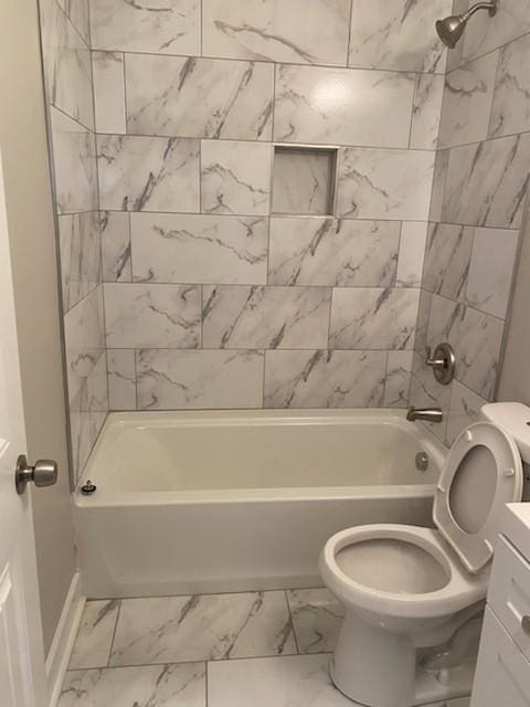 full bath featuring marble finish floor, shower / bathing tub combination, toilet, vanity, and baseboards