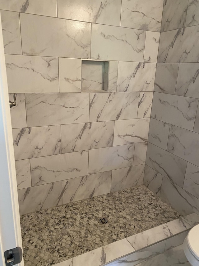 full bath with toilet and a tile shower