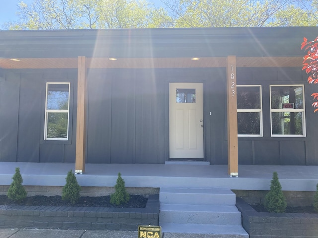 view of exterior entry with a porch and board and batten siding