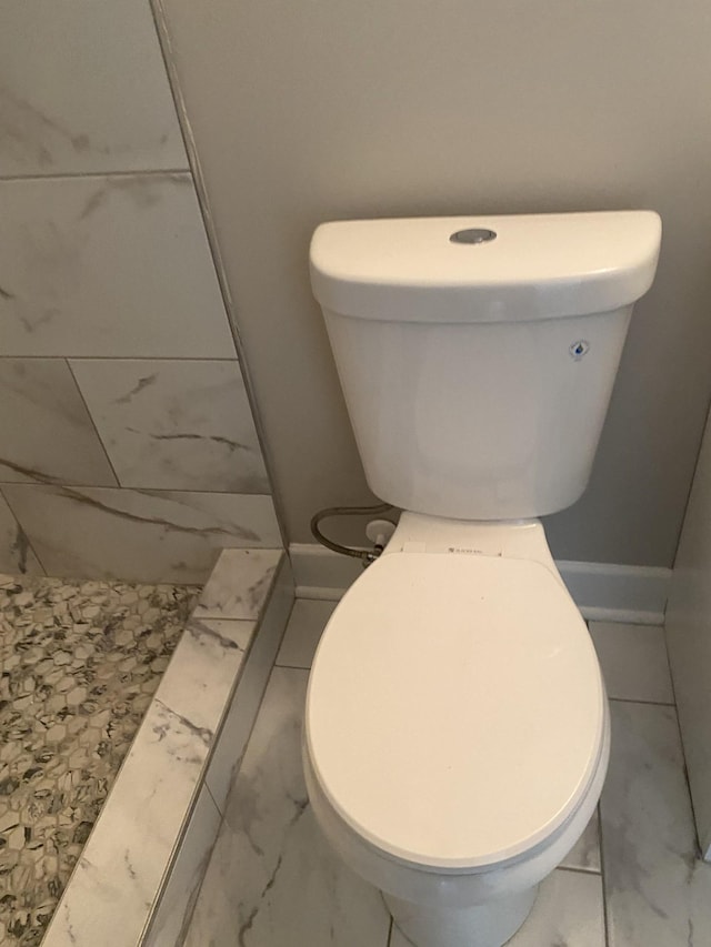bathroom featuring toilet, marble finish floor, and baseboards