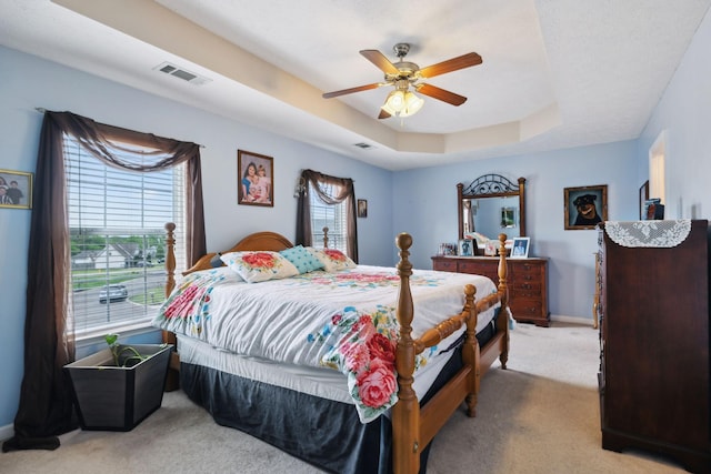 bedroom featuring a raised ceiling, visible vents, multiple windows, and light carpet