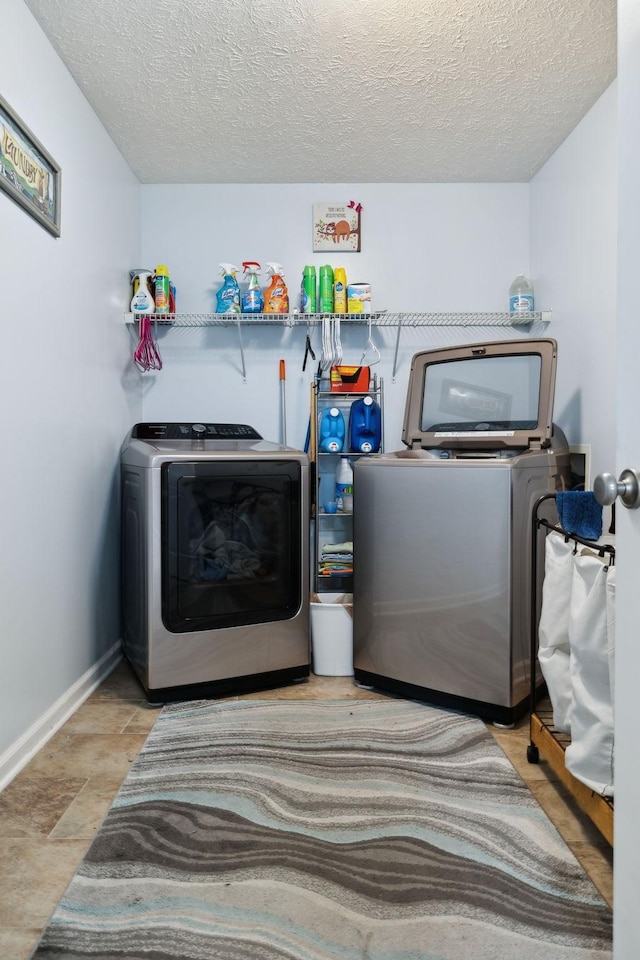 laundry area with a textured ceiling, washer and clothes dryer, laundry area, and baseboards