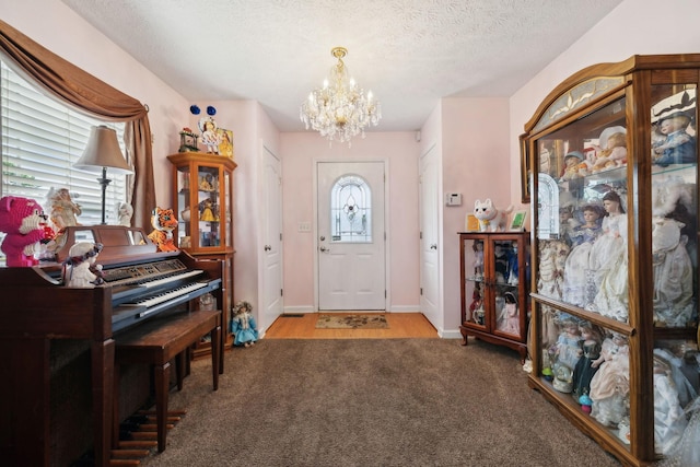 carpeted foyer entrance featuring a chandelier, baseboards, and a textured ceiling