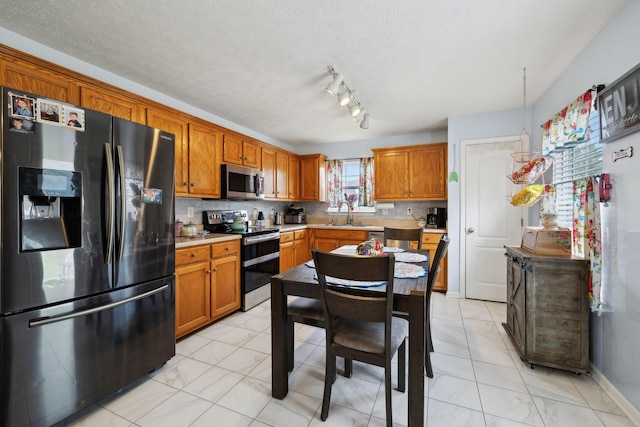 kitchen with brown cabinets, appliances with stainless steel finishes, light countertops, and a sink