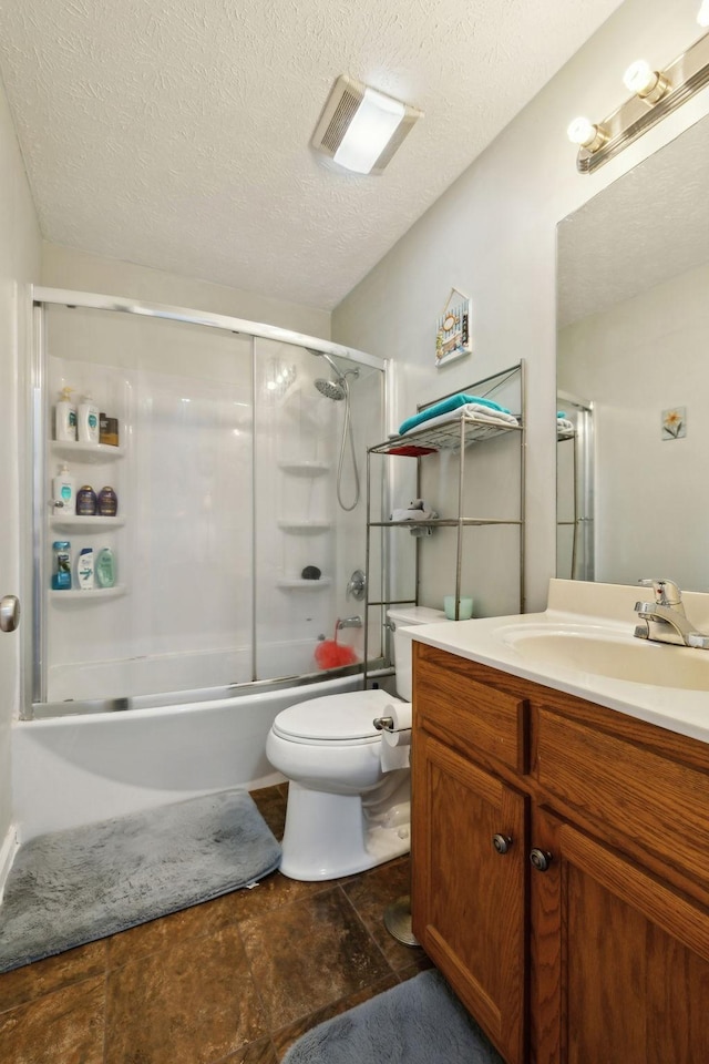 full bath featuring toilet, vanity, visible vents, bath / shower combo with glass door, and a textured ceiling