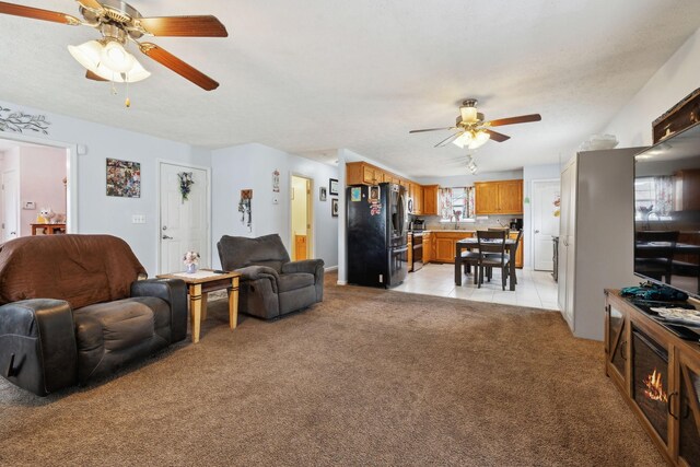 living room featuring light tile patterned floors, a ceiling fan, and light carpet