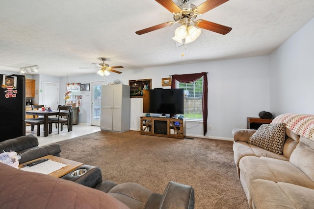 living room with a ceiling fan, light carpet, a textured ceiling, and baseboards