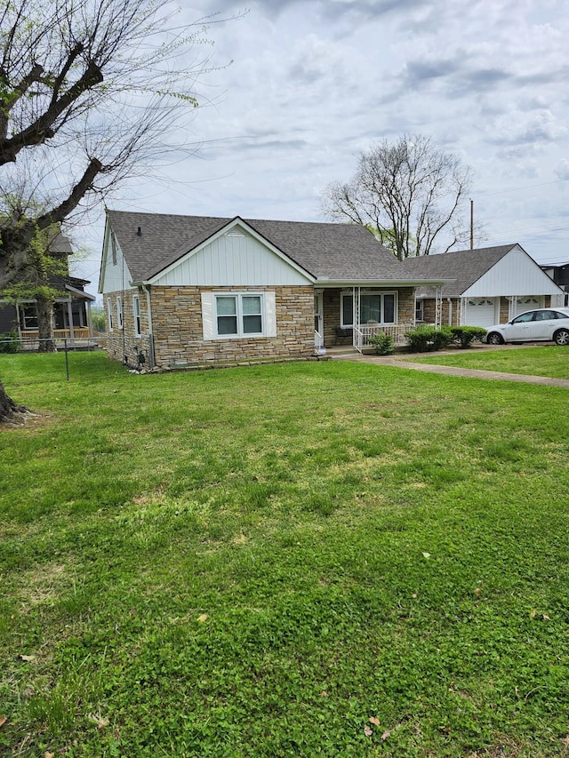 view of front of property with a shingled roof, a front lawn, an attached garage, and stone siding