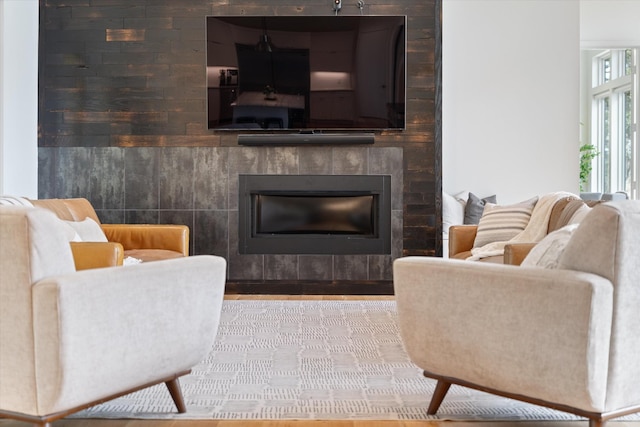 living area with a tile fireplace and wood finished floors