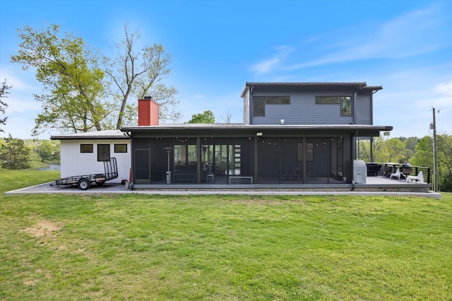 rear view of property with a sunroom, a lawn, and a chimney