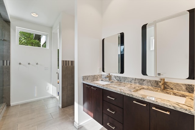 bathroom featuring tile patterned floors, a stall shower, double vanity, and a sink