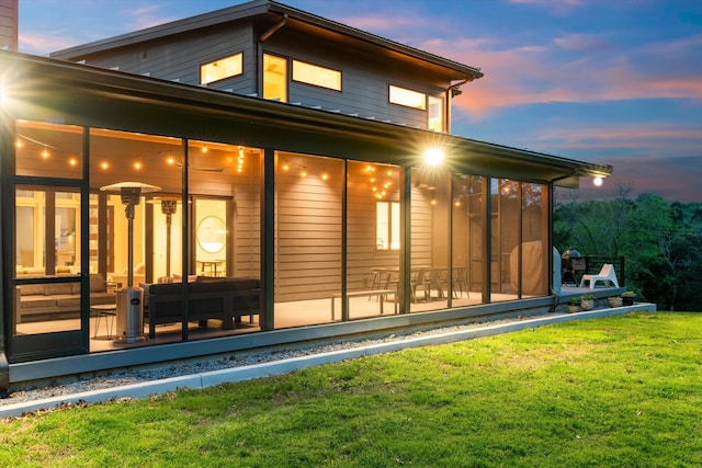 back of house with a sunroom and a lawn