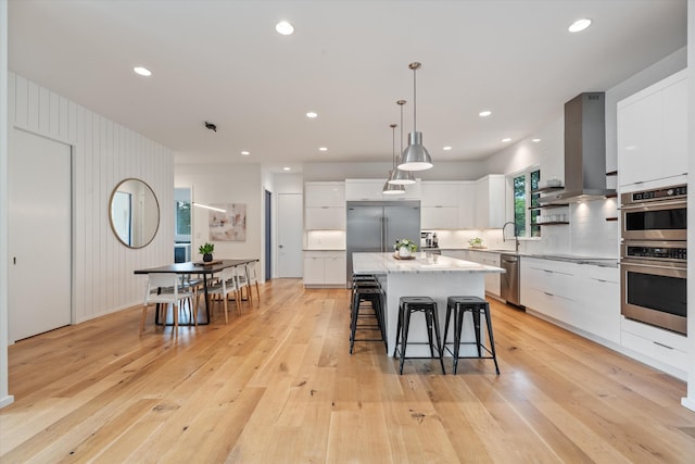 kitchen featuring a breakfast bar area, island exhaust hood, modern cabinets, and stainless steel appliances