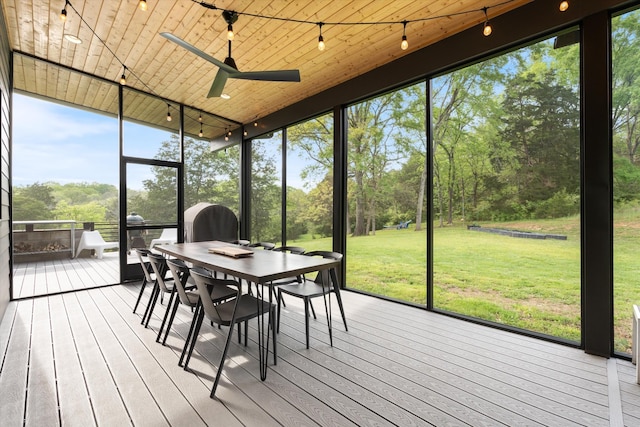 sunroom featuring rail lighting, outdoor dining space, and a ceiling fan
