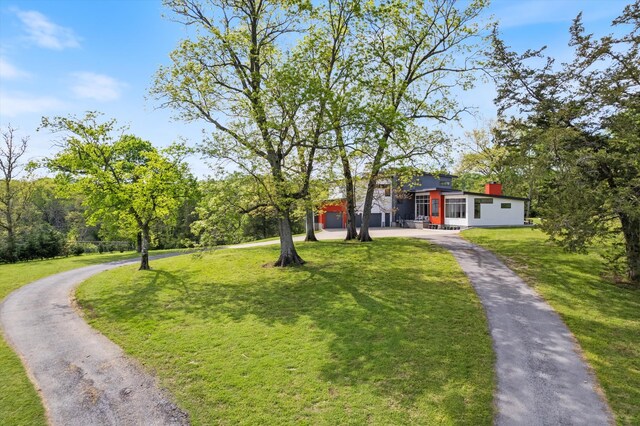view of front of property featuring a front lawn and curved driveway